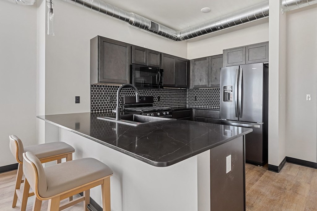 A kitchen with a black counter top and a refrigerator.