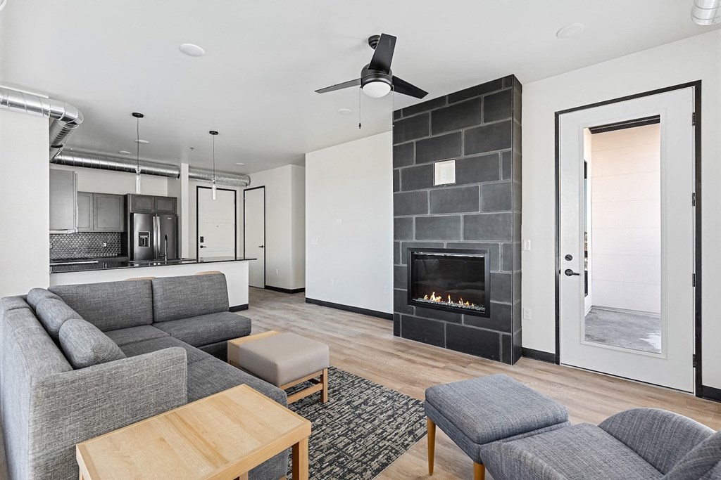 A modern living room with a grey couch, a wooden coffee table, and a fireplace.