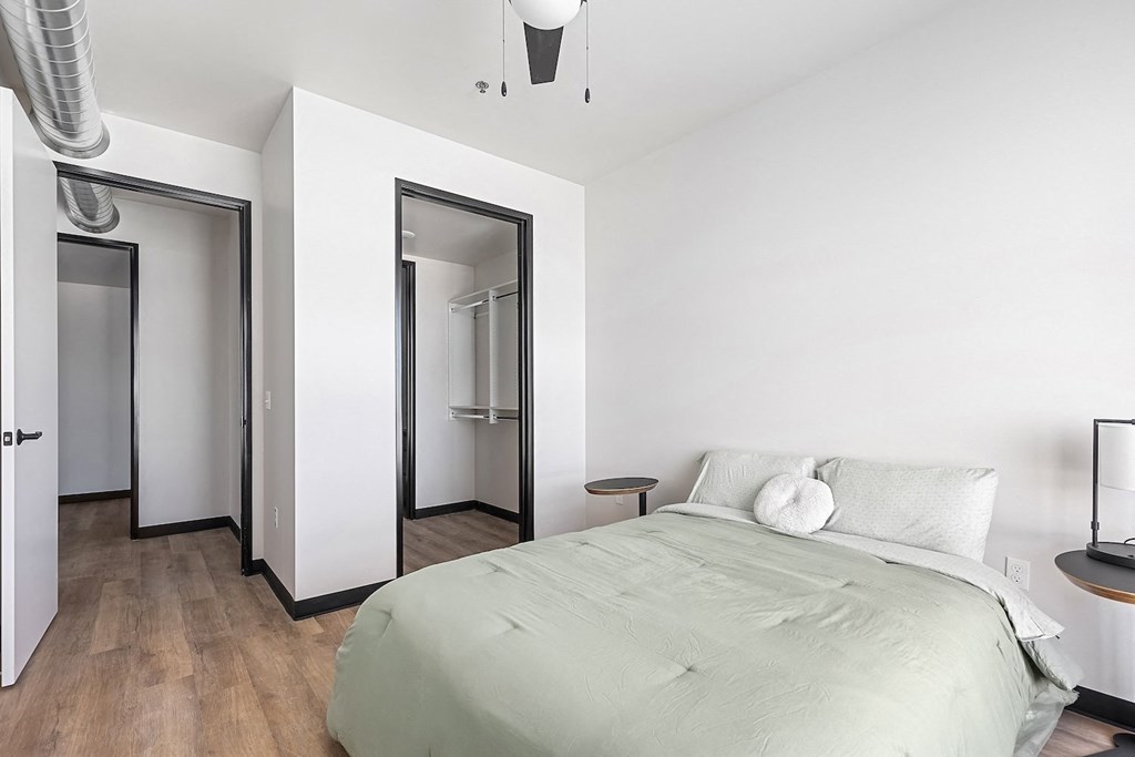 A bedroom with a bed, nightstand, and mirrors.