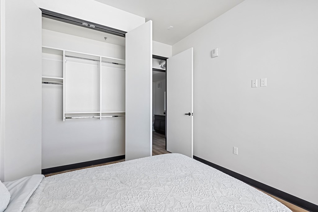 A white bedroom with a bed and a closet.