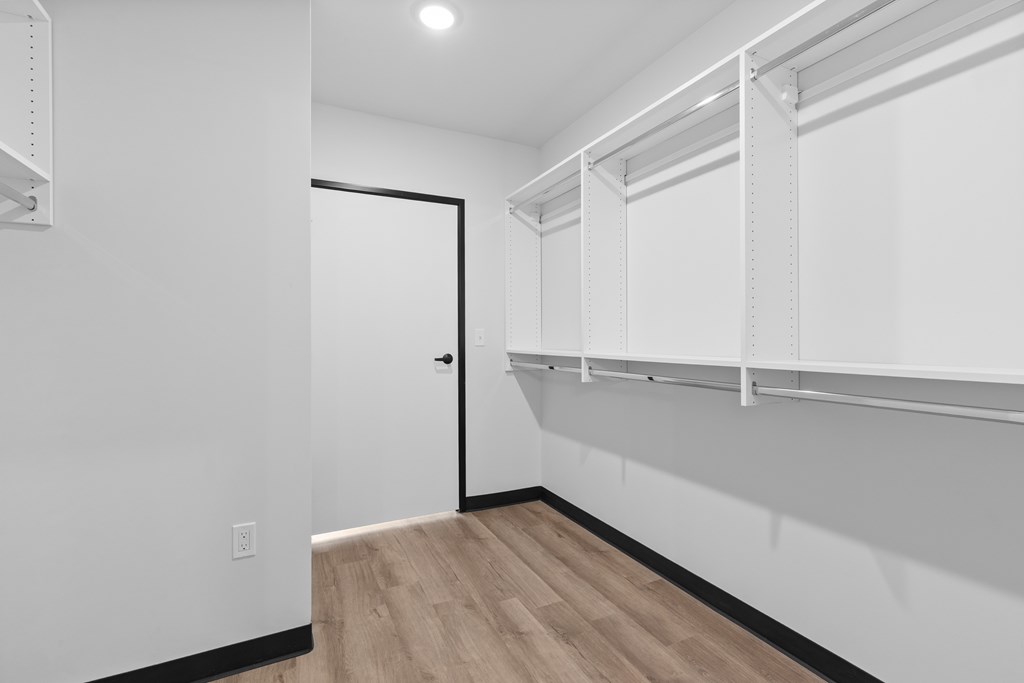 A white room with a door and a shelf.