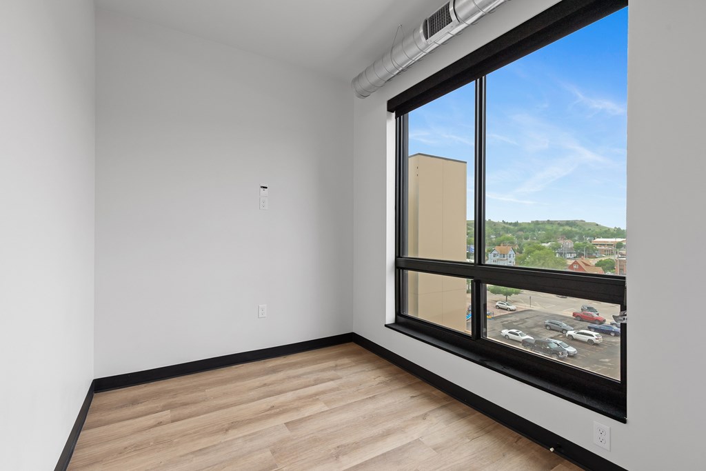 A room with a large window overlooking a parking lot.