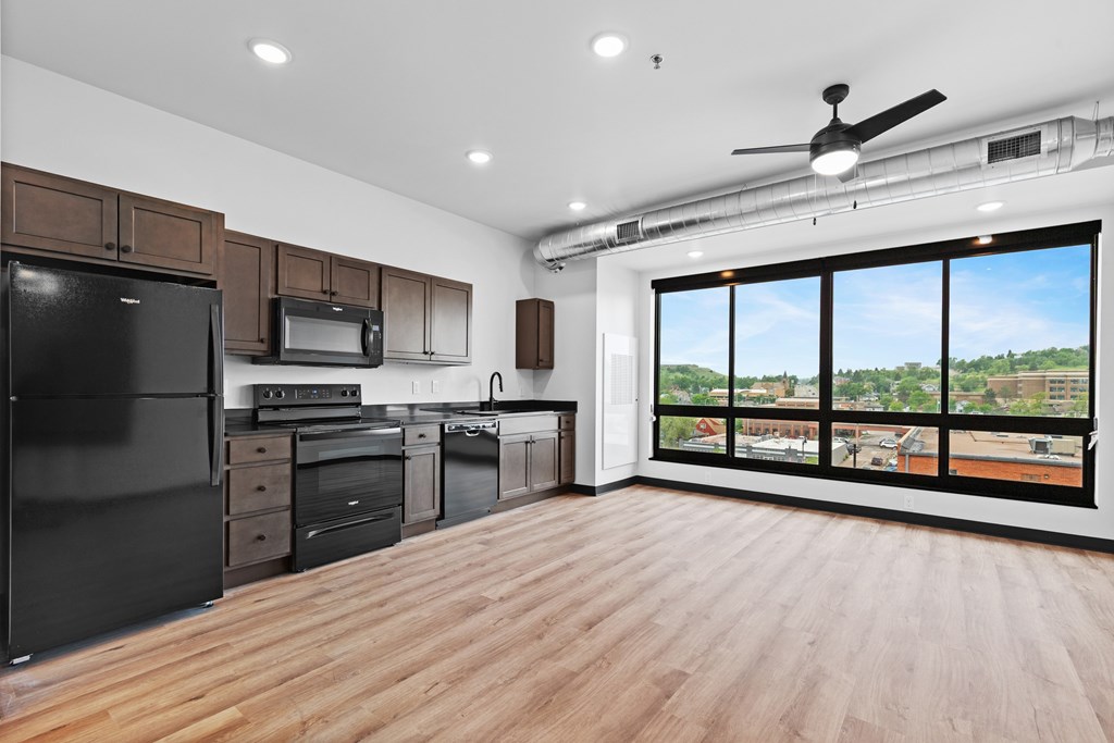 A spacious kitchen with wooden floors and a large window overlooking the city.