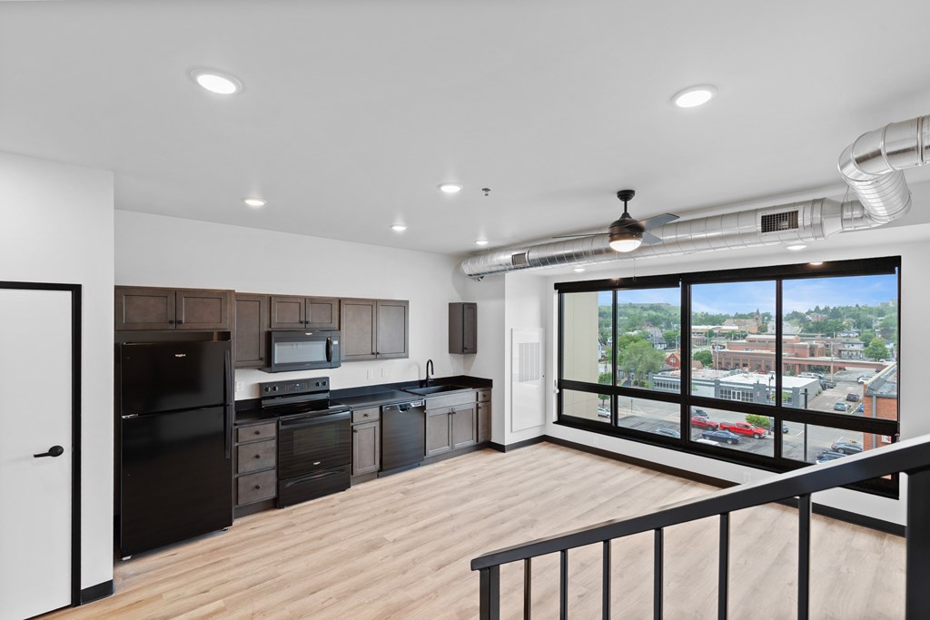 A modern kitchen with black appliances and wooden floors.