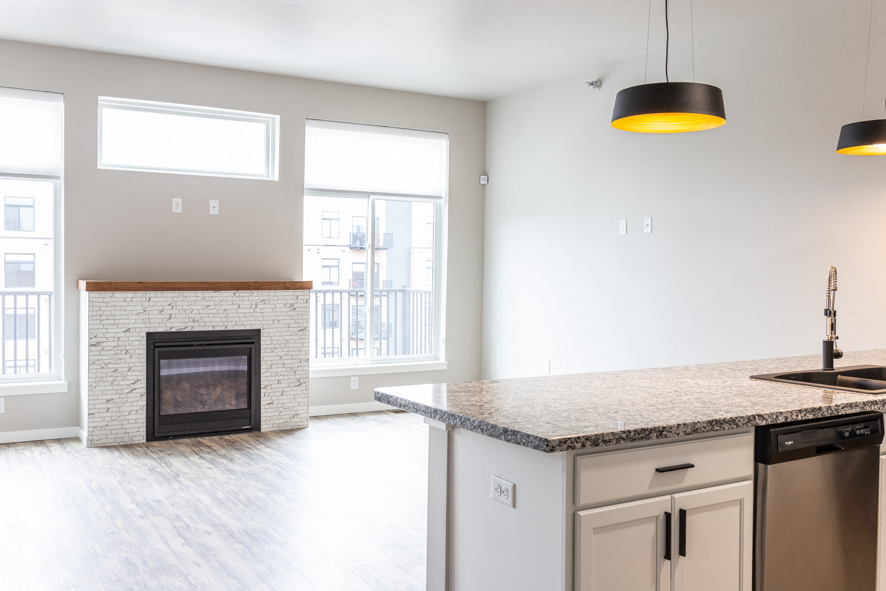 an empty living room with a fireplace and a kitchen