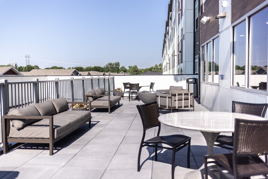 a rooftop patio with tables and chairs and a building