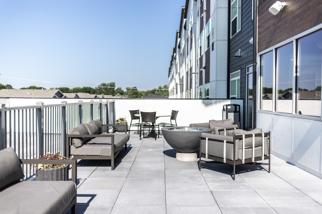 a terrace with couches and chairs and a table on a balcony