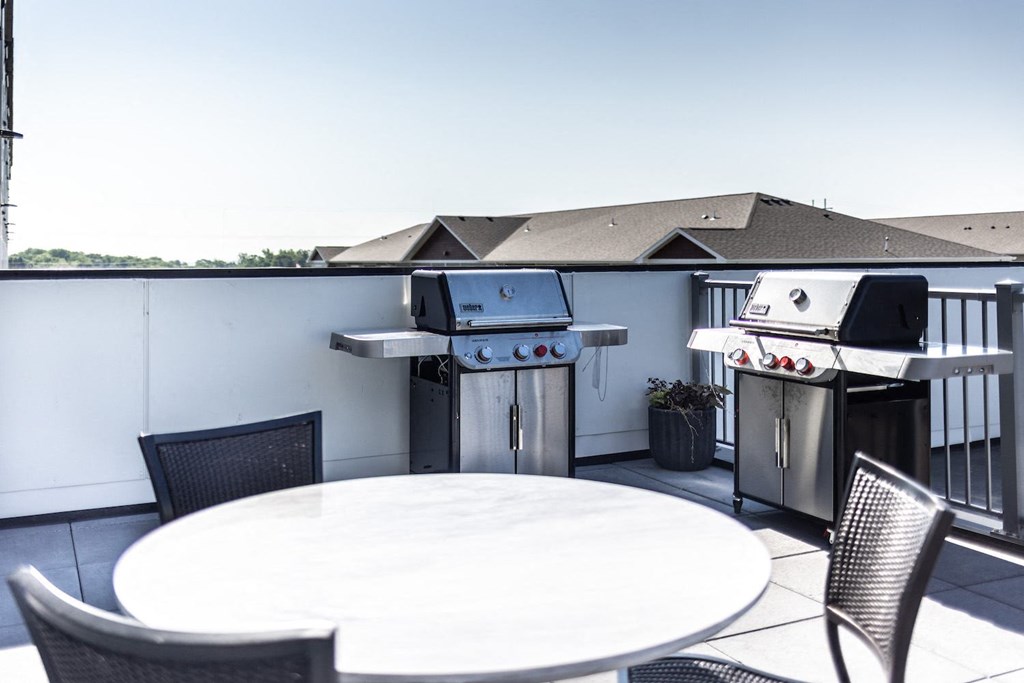 a patio with two barbecue grills and a table