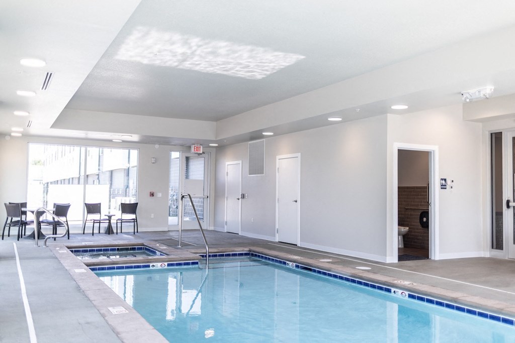 a large swimming pool in a room with chairs and a door