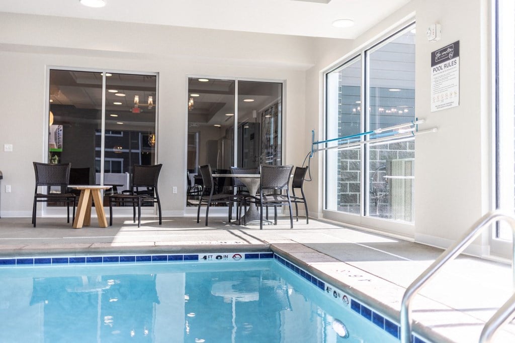 the pool area of a building with a swimming pool and tables and chairs