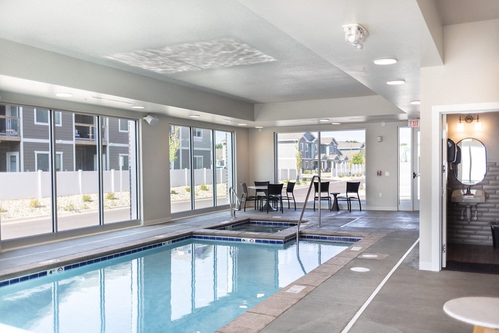 a swimming pool in the middle of a room with a table and chairs