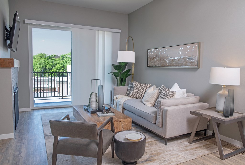 a living room with a couch and a chair and a door to a balcony