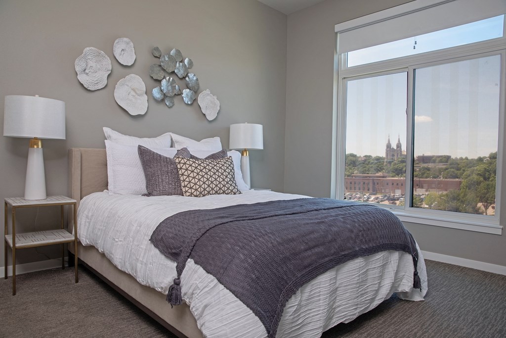 a bedroom with a large window and a bed with pillows