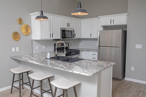 a kitchen with white cabinets and a counter top with stools