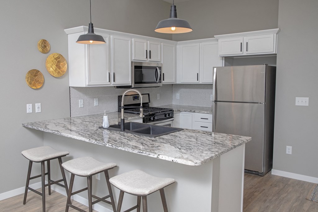 a kitchen with white cabinets and a counter top with stools
