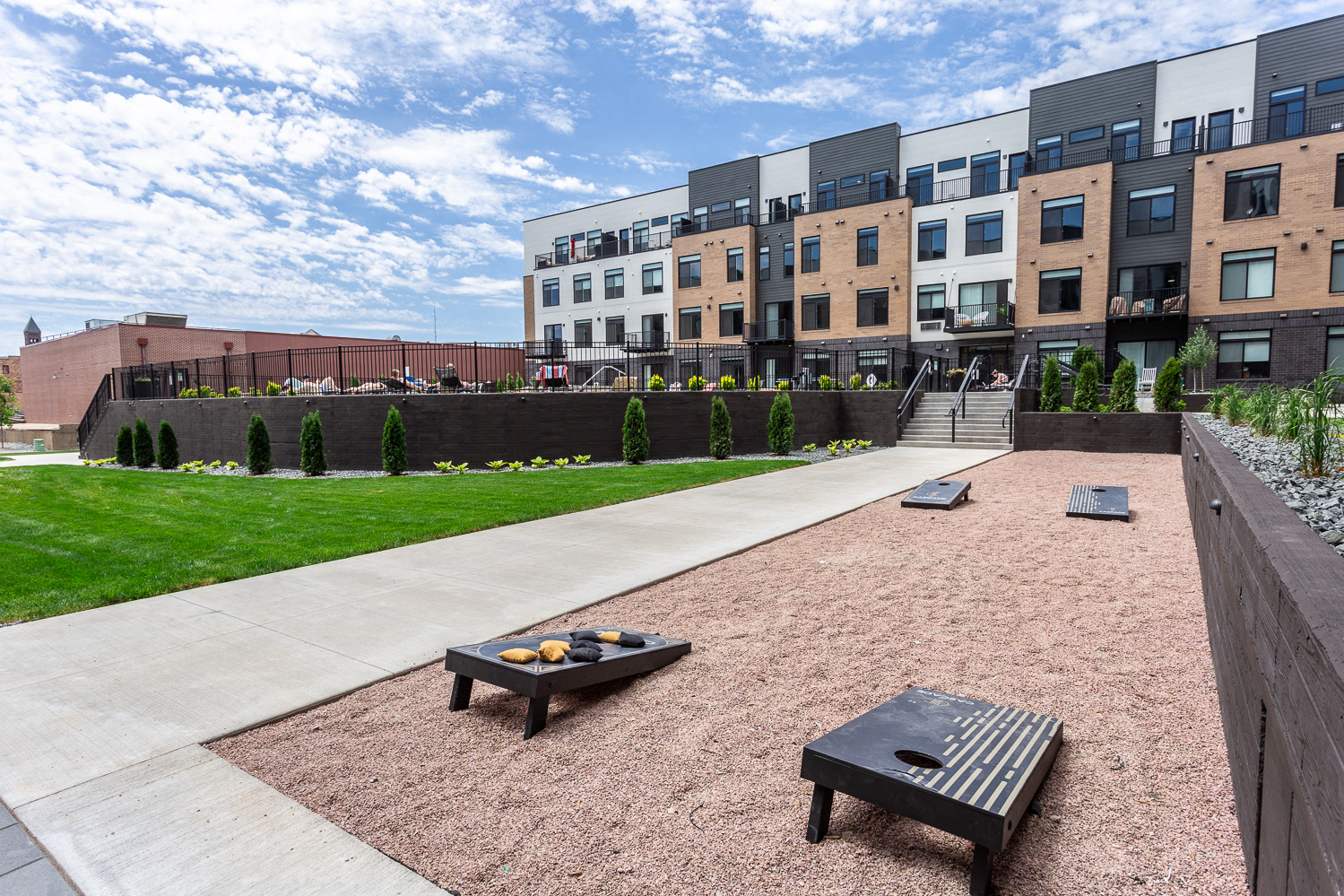 a courtyard with benches and grass in front of an apartment building