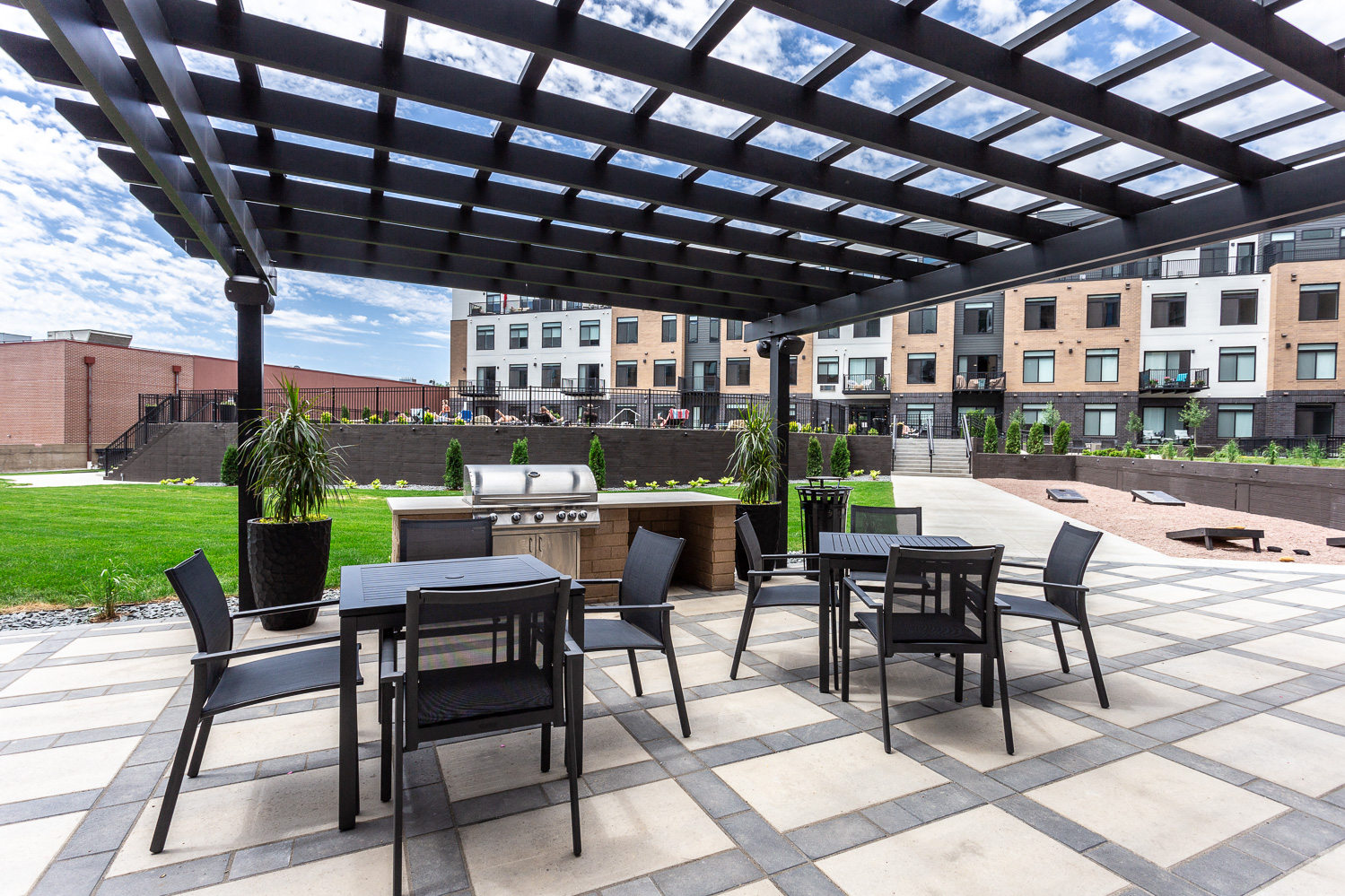 an outdoor patio with tables and chairs and a grill