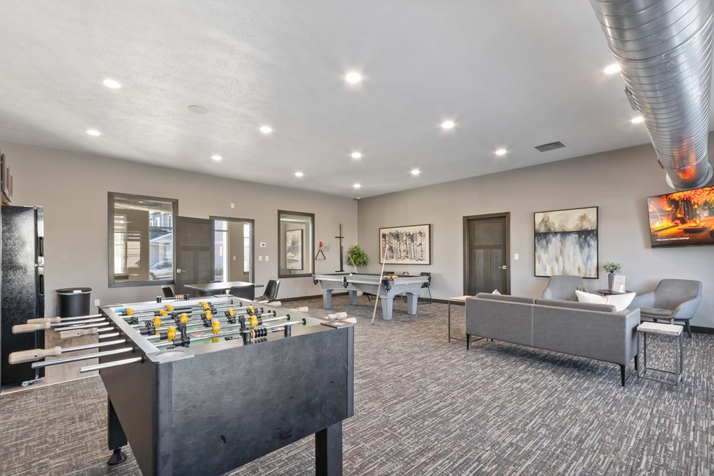 A foosball table is in the middle of a room with a couch and a chair.