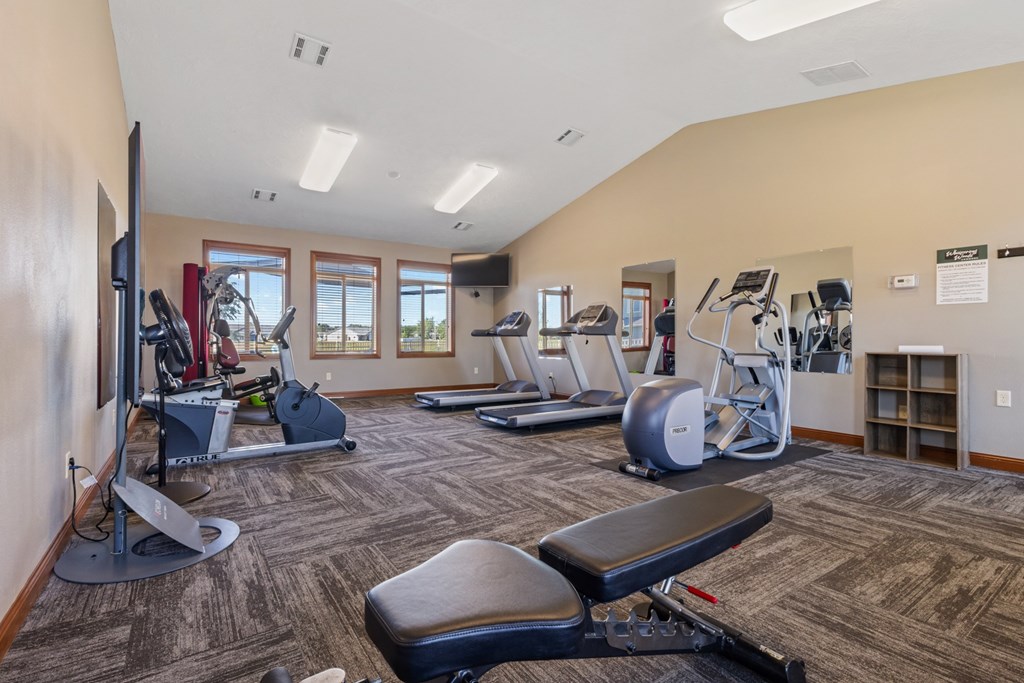 A gym with a variety of equipment including treadmills, weights, and exercise machines.