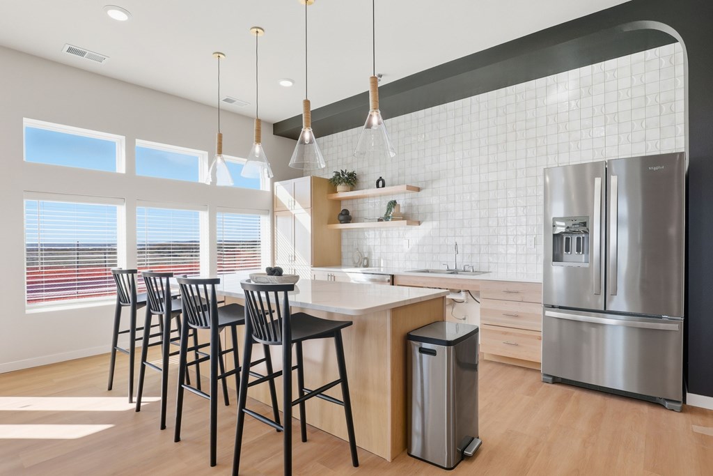 A modern kitchen with a bar area and a refrigerator.