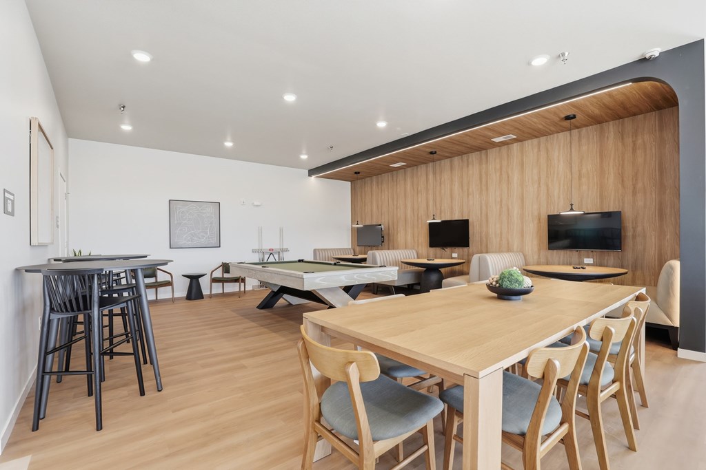A modern dining room with a long wooden table and chairs.