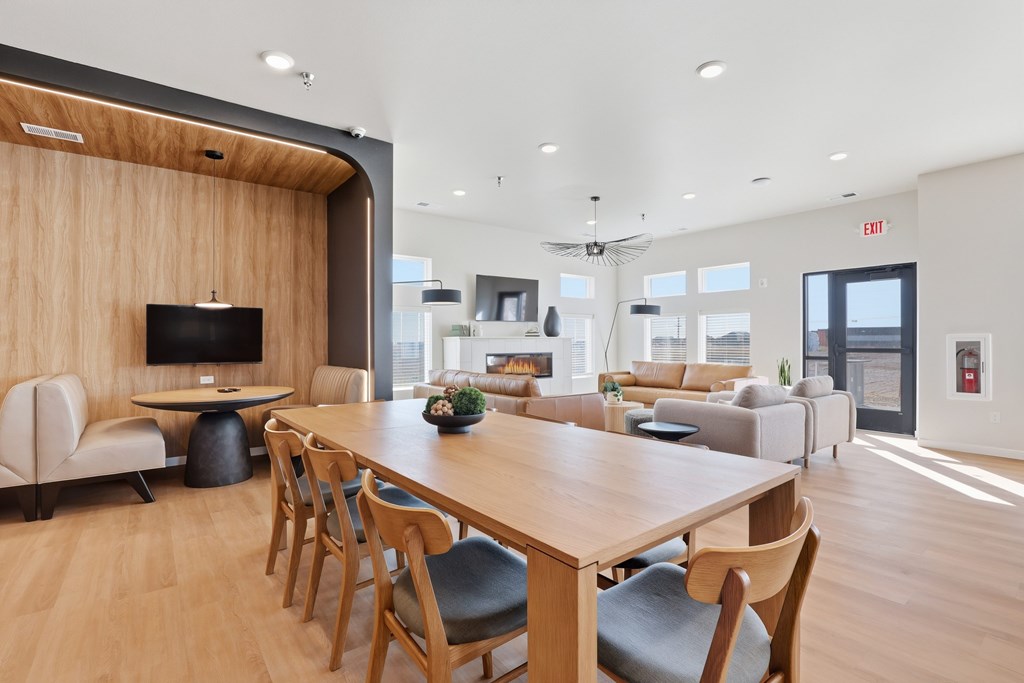 A modern dining room with a long wooden table and chairs.