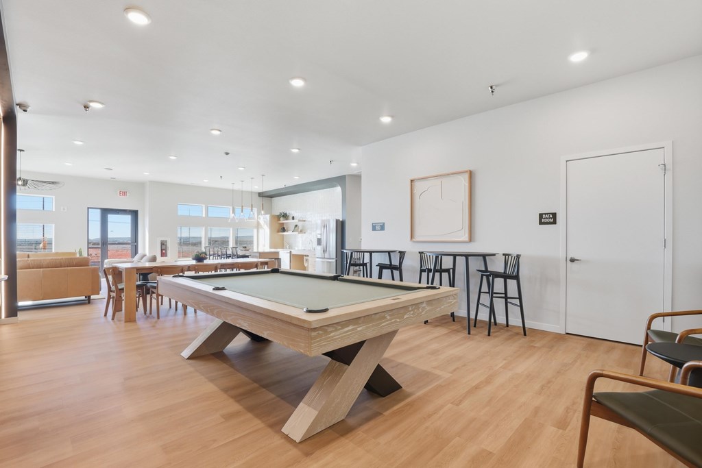 A billiard table is in the middle of a room with a white wall and a door.