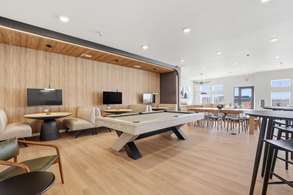 A room with a pool table and chairs.