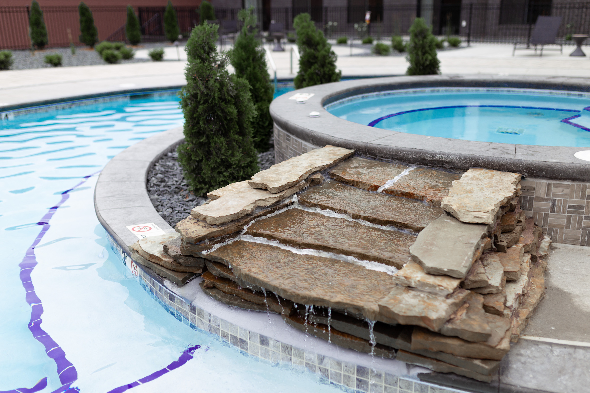 a stone fountain in the middle of a swimming pool
