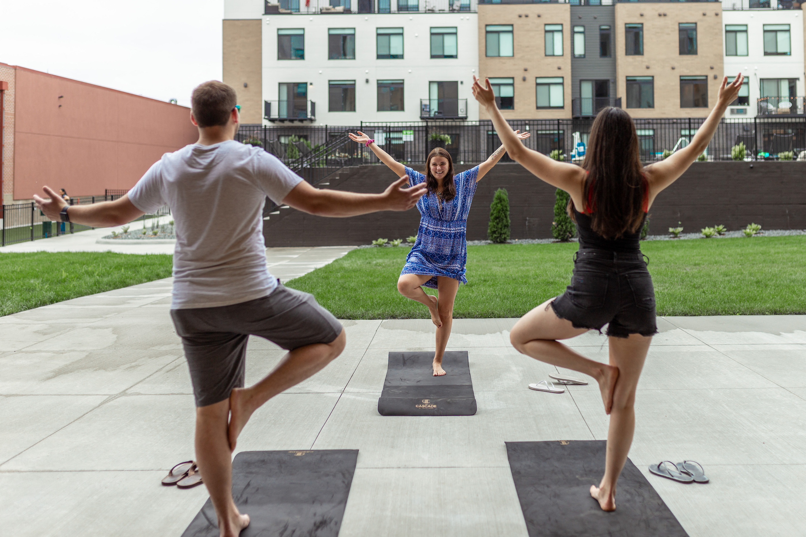 a man and two women doing yoga on benches in a park