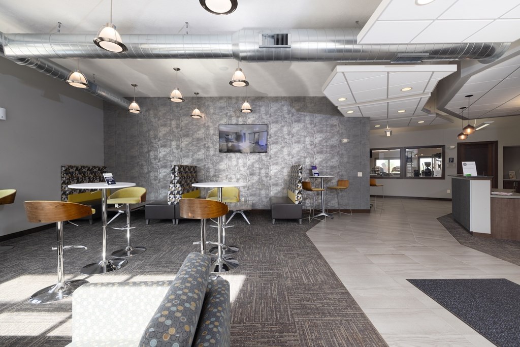 A modern office space with a grey stone wall and a long carpeted table.