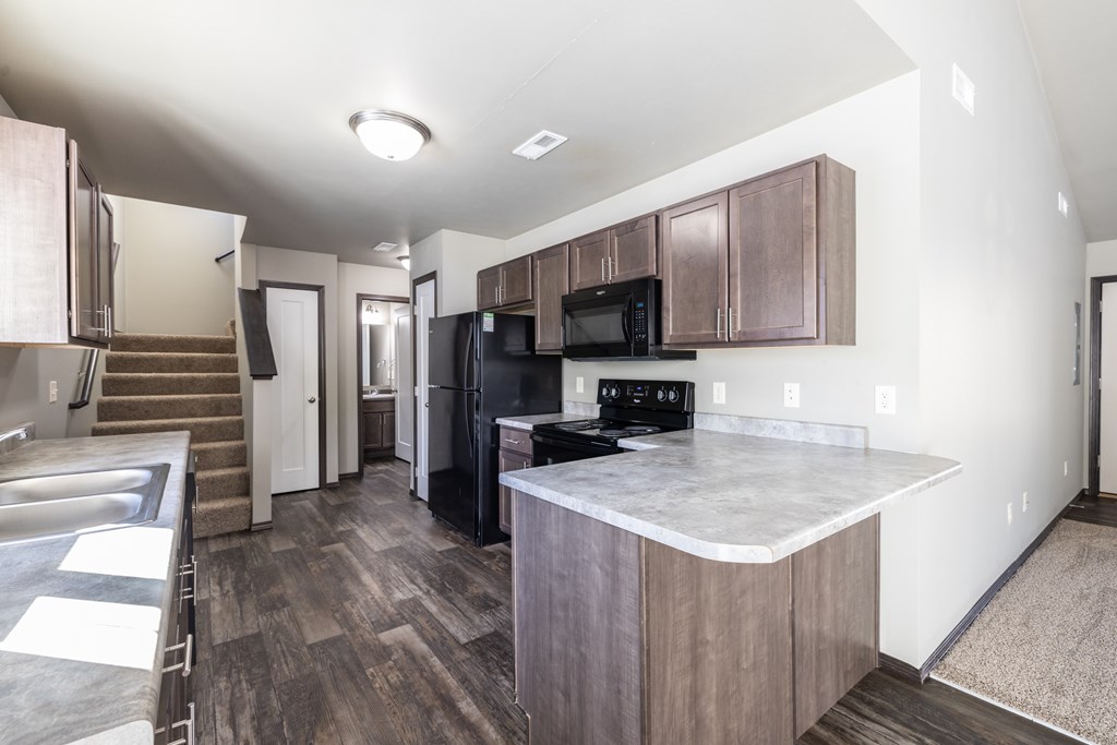 A kitchen with a black fridge and microwave.