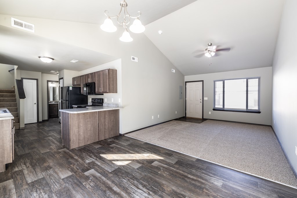 A spacious living room with a kitchen area in the background.