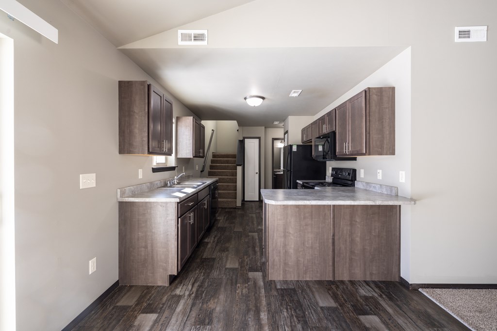 A kitchen with wooden floors and a black refrigerator.
