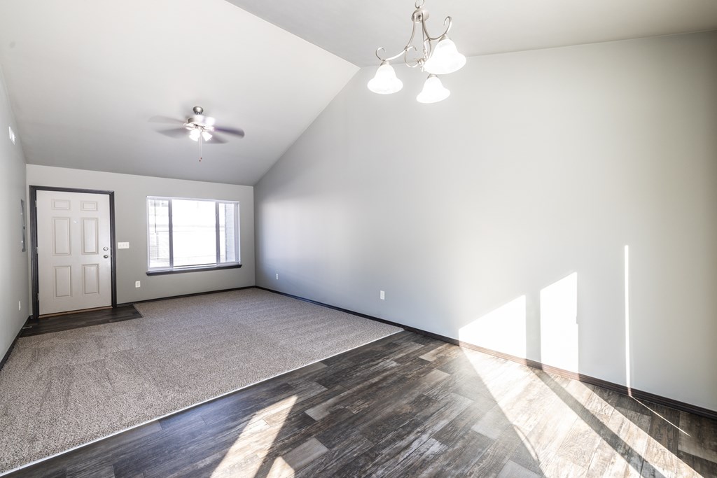 A spacious room with a ceiling fan and a door.