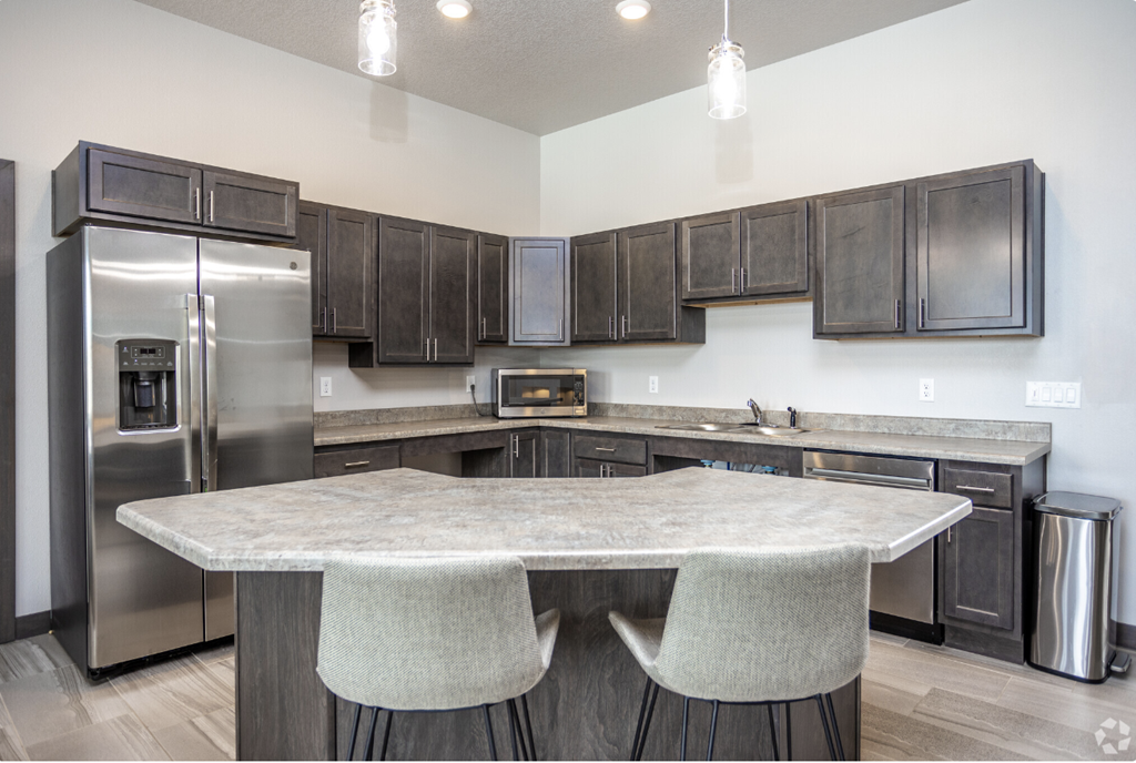 Spacious community room with fireplace, kitchen, and lounge seating.