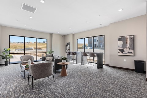 a lounge area with chairs and a bar in a building with large windows