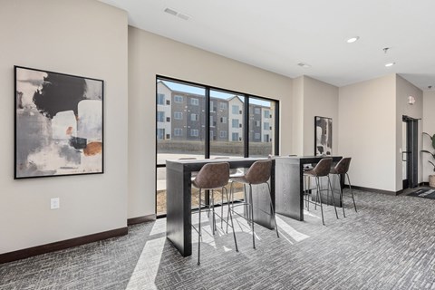 a communal area with a bar and chairs and a large window