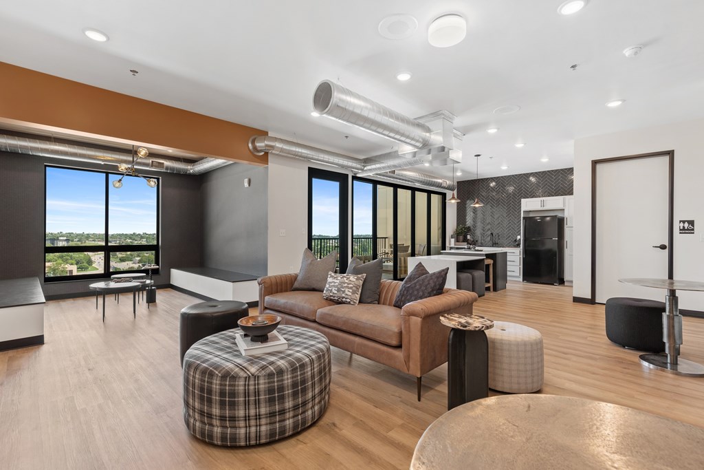 A modern living room with a brown couch and a checkered ottoman.