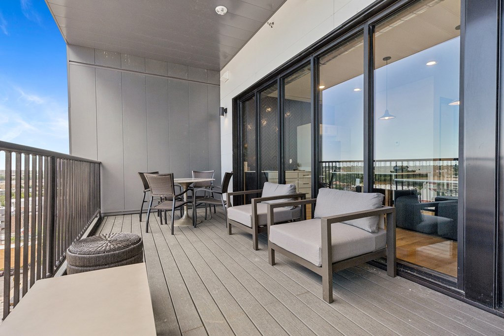 A balcony with a table and chairs overlooking a cityscape.
