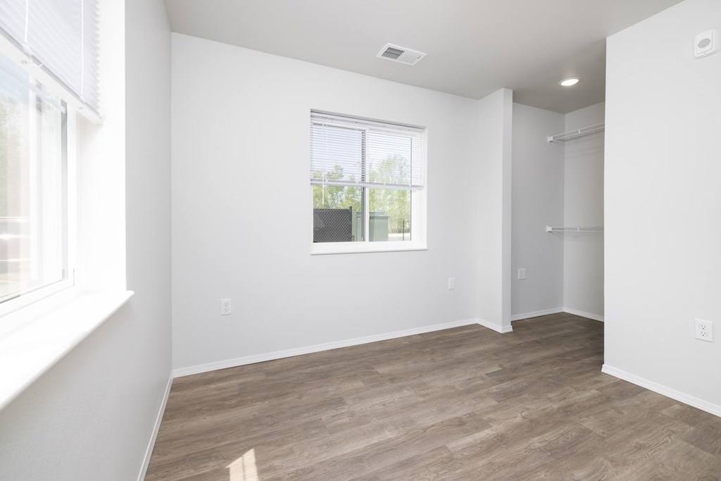 A room with a window and a wooden floor.