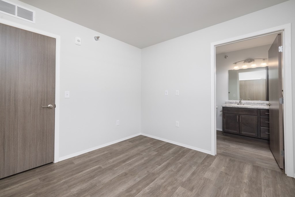 A room with a wooden floor and a door on the left.
