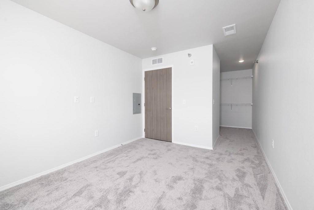 A room with a carpeted floor and a wooden door.