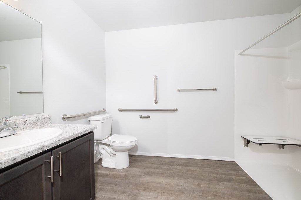 A white bathroom with a toilet, sink, and a bench.