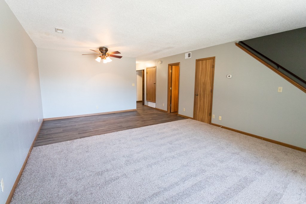 the living room of an empty house with a ceiling fan