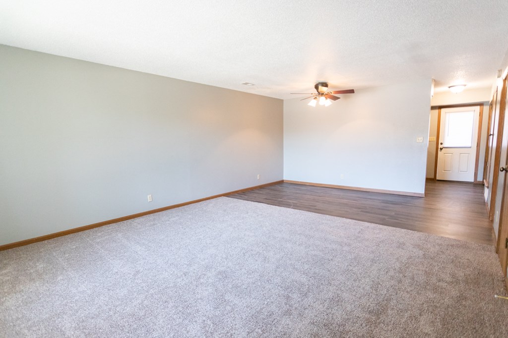 the living room and dining room of an empty house with a ceiling fan