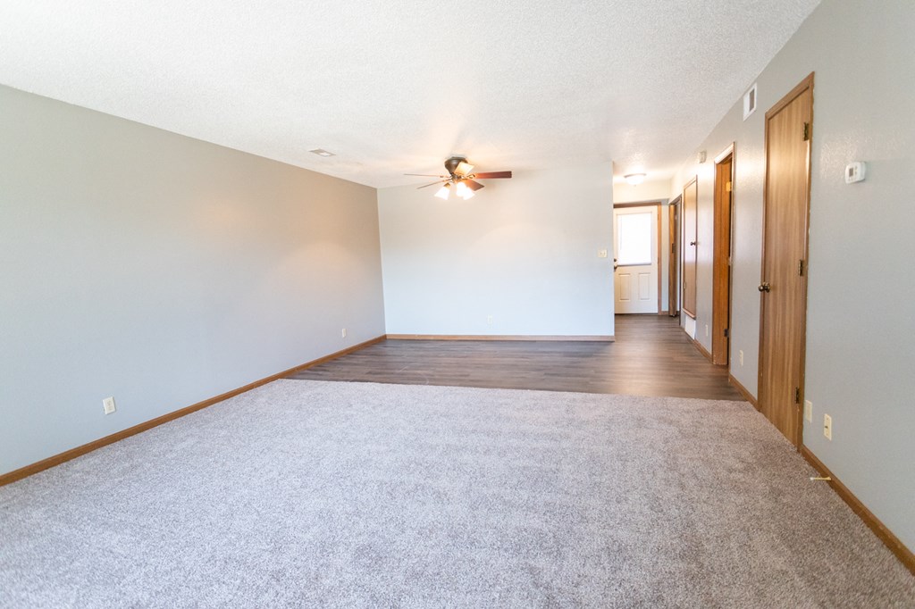an empty living room with white walls and a ceiling fan
