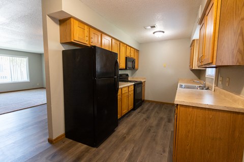 a kitchen with a black refrigerator and wooden cabinets