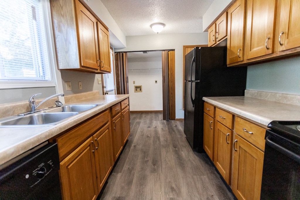 a kitchen with wooden cabinets and a black refrigerator