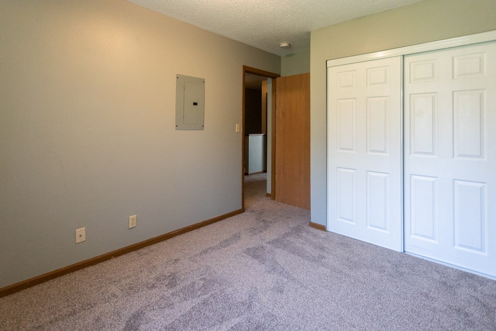 an empty living room with two closets and a door to a hallway
